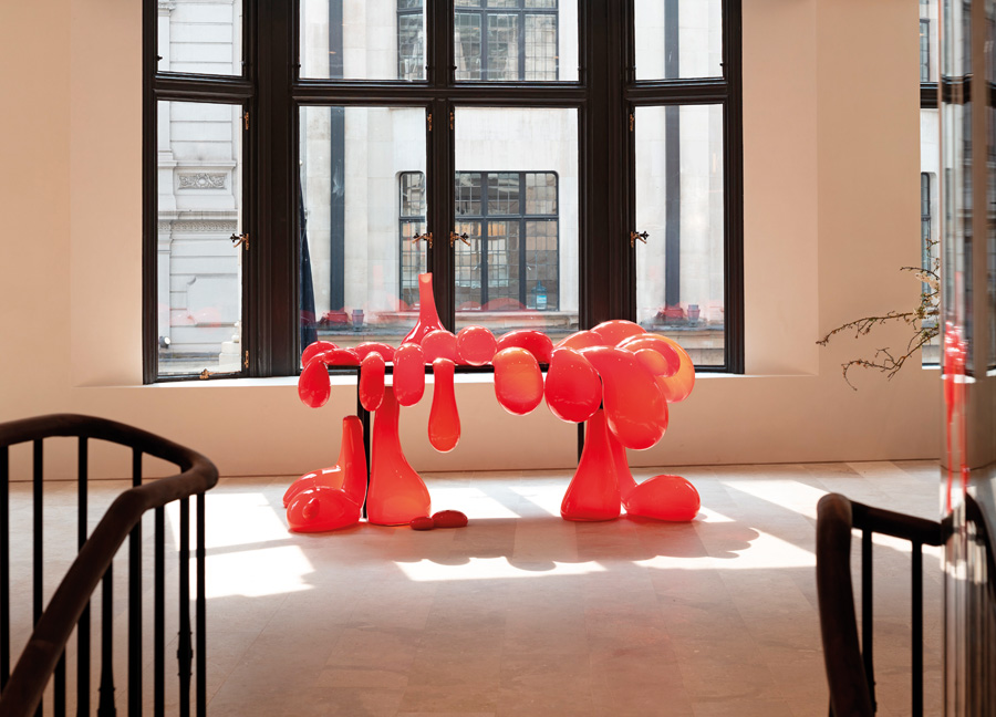 Escultura de diseño en forma de gotas rojas junto a una ventana en Loewe