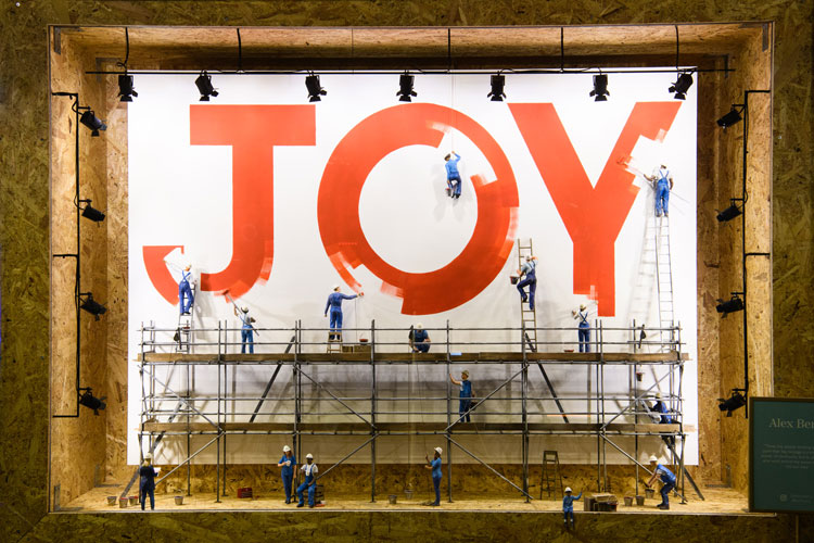 Escaparate de pintores escribiendo la palabra "JOY" en una colaboración de escaparates